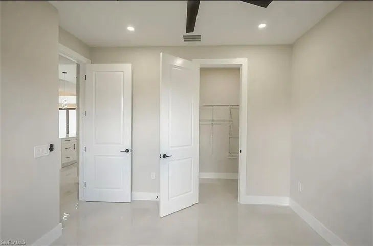 Unfurnished bedroom with a spacious closet, ceiling fan, and a closet