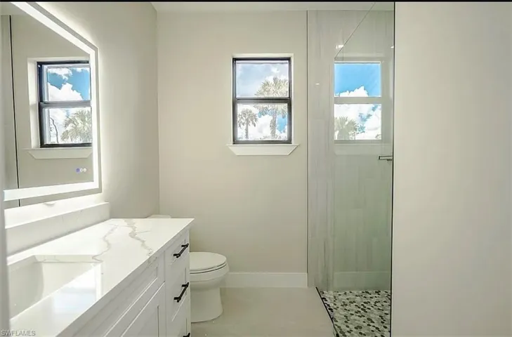Bathroom featuring walk in shower, vanity, toilet, and tile patterned floors