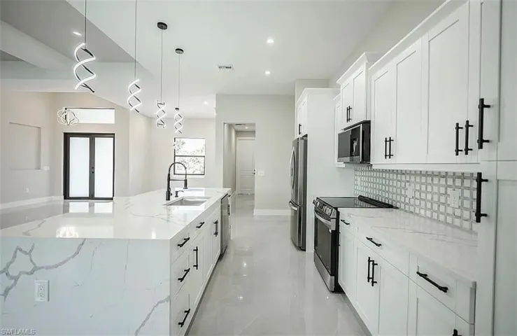 Kitchen with pendant lighting, sink, light stone counters, and stainless steel appliances
