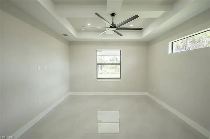 Unfurnished room featuring a wealth of natural light, a raised ceiling, and concrete floors