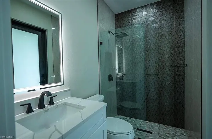 Bathroom featuring tiled shower, vanity, and toilet