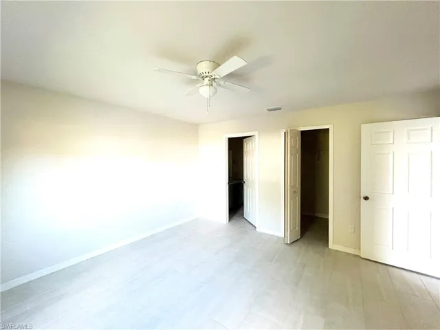 Unfurnished bedroom with a walk in closet, ceiling fan, and a closet