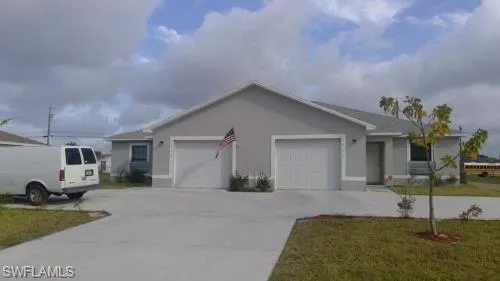 Ranch-style home with an attached garage, stucco siding, driveway, and a front lawn