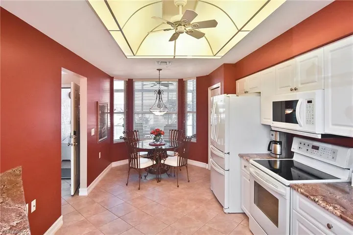 Kitchen with white appliances, white cabinetry, decorative light fixtures, a ceiling fan, and light tile patterned flooring