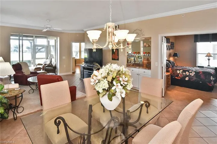 Dining space featuring light tile patterned floors, healthy amount of natural light, crown molding, a ceiling fan, and a chandelier