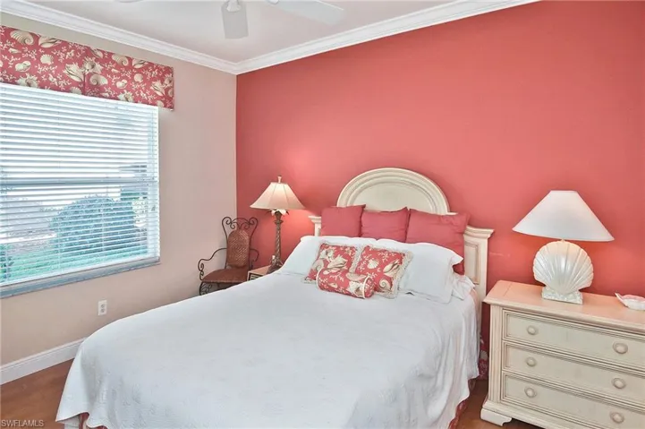 Bedroom with a ceiling fan, wood finished floors, and ornamental molding