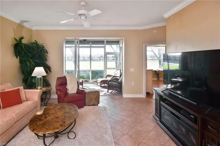 Living room with crown molding, light tile patterned floors, and ceiling fan