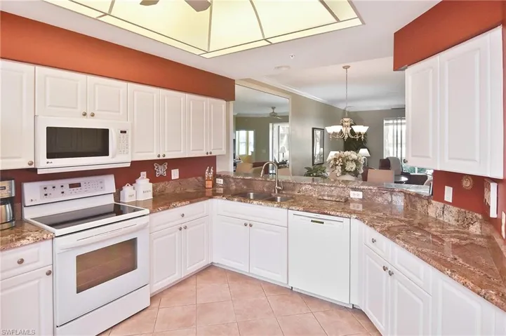 Kitchen featuring white appliances, a ceiling fan, white cabinets, and ornamental molding