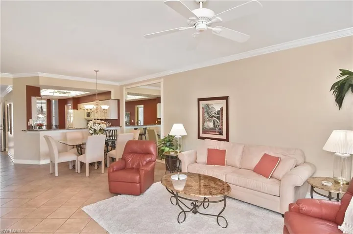Living room featuring crown molding, light tile patterned floors, a chandelier, and ceiling fan