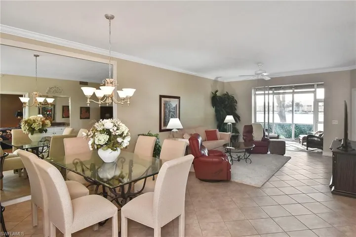 Dining area with crown molding, ceiling fan, light tile patterned floors, and a chandelier