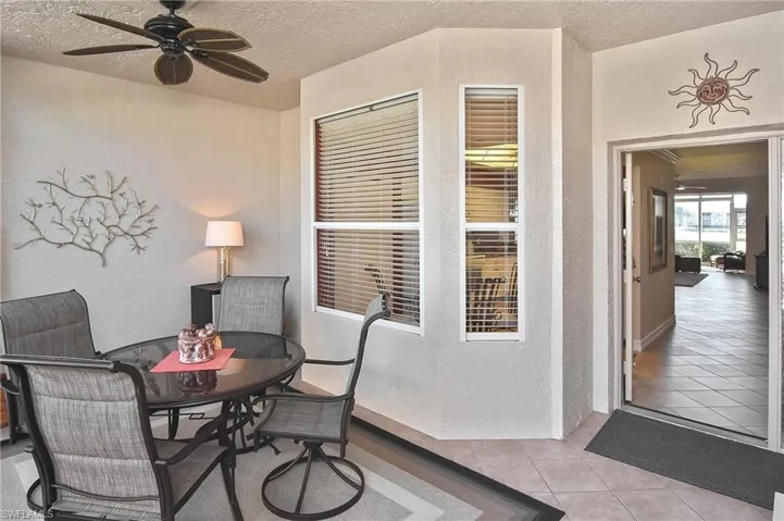 Dining room featuring a textured wall, a ceiling fan, light tile patterned floors, and a textured ceiling