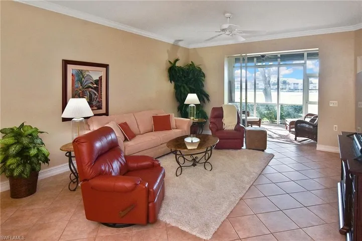 Living room featuring crown molding, light tile patterned floors, and a ceiling fan