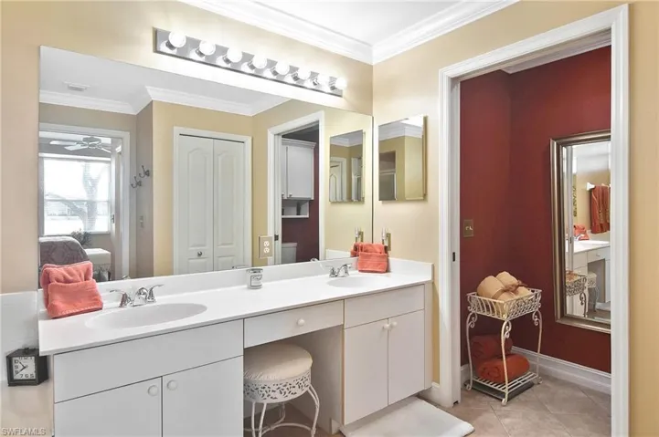 Ensuite bathroom featuring ornamental molding, double vanity, light tile patterned floors, and a closet