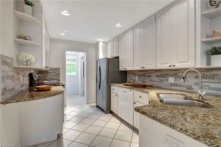 Kitchen featuring white cabinetry, sink, tasteful backsplash, light stone countertops, and white appliances