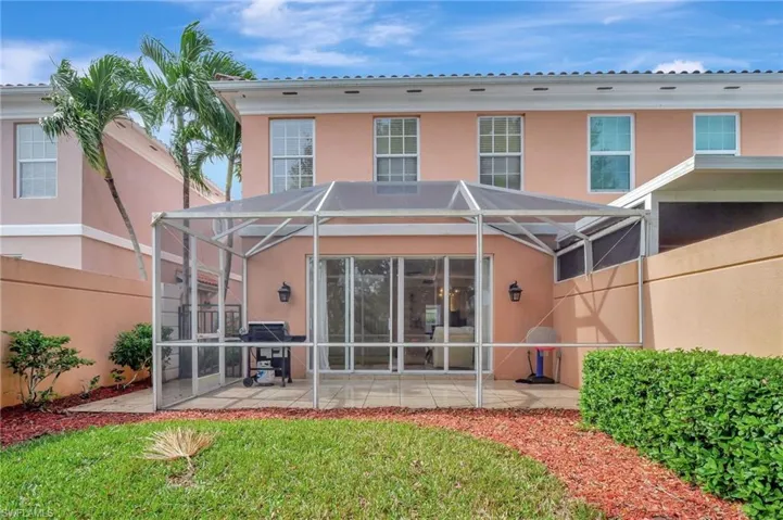 Rear view of property featuring glass enclosure and a patio area