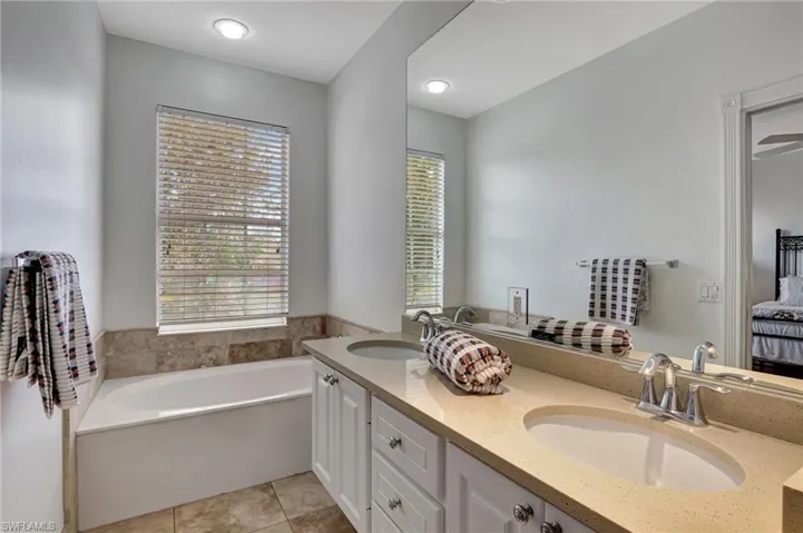 Bathroom with vanity, ceiling fan, tile patterned flooring, and a bathtub