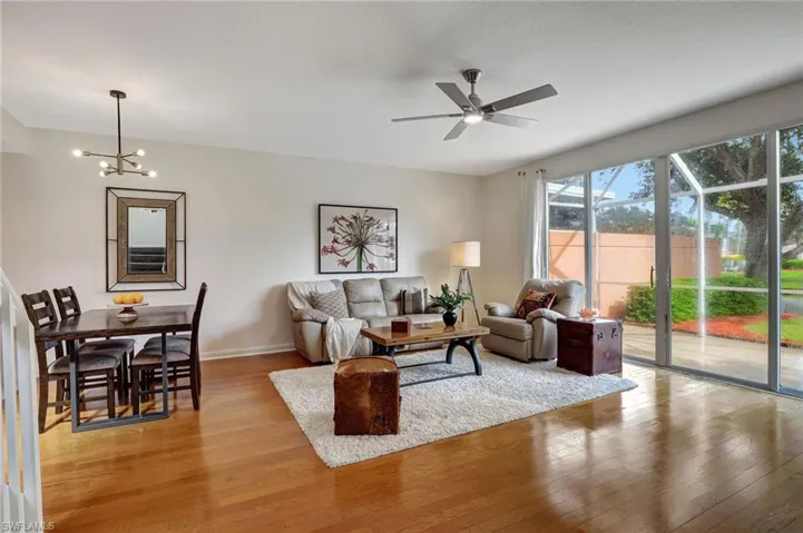 Living room with light hardwood / wood-style floors and ceiling fan with notable chandelier