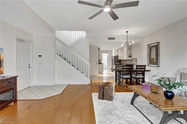 Living room with ceiling fan with notable chandelier and light wood-type flooring