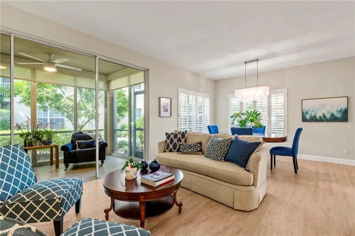 Living room with ceiling fan with notable chandelier and wood-type flooring