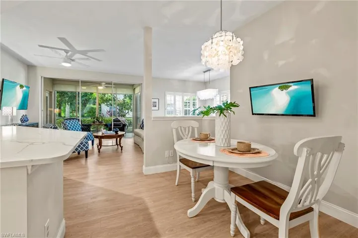 Dining room with light hardwood / wood-style flooring and ceiling fan with notable chandelier
