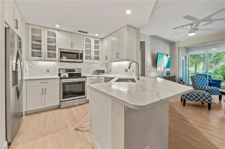 Kitchen with white cabinetry, stainless steel appliances, sink, light hardwood / wood-style flooring, and kitchen peninsula