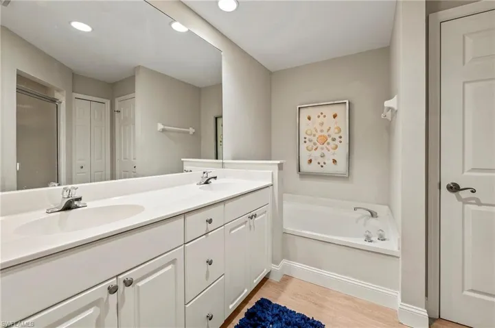 Master Bathroom featuring double vanity, wood-type flooring, and a tub