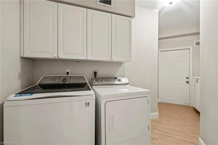Laundry room featuring washer and dryer, light hardwood / wood-style flooring, and cabinets
