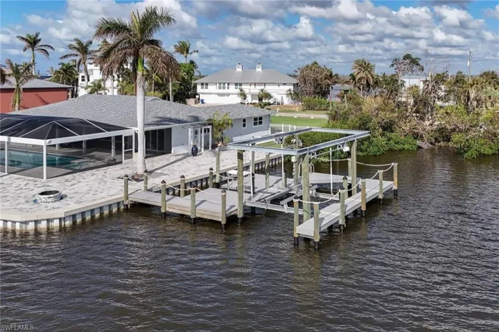 View of dock with glass enclosure, a swimming pool, a water view, and a patio