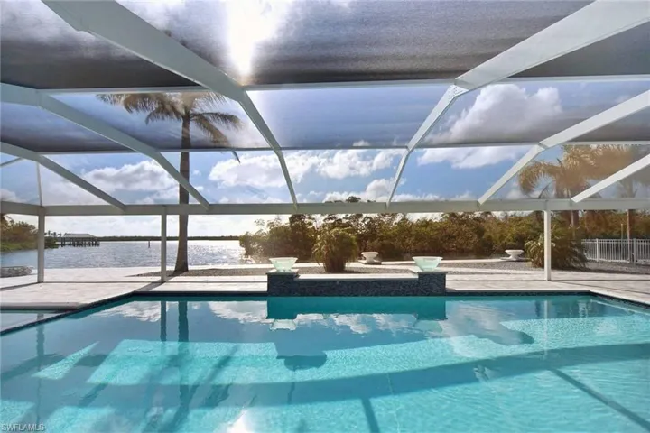 View of pool featuring a patio, a water view, and glass enclosure