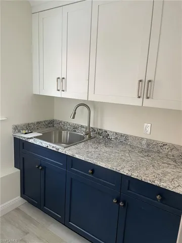 Kitchen with light hardwood / wood-style floors, white cabinetry, blue cabinets, and sink