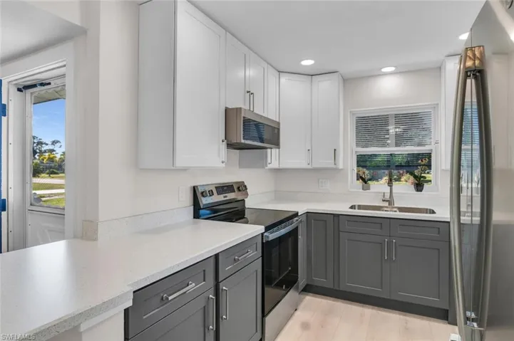 Kitchen with stainless steel appliance finishes, gray and white cabinets