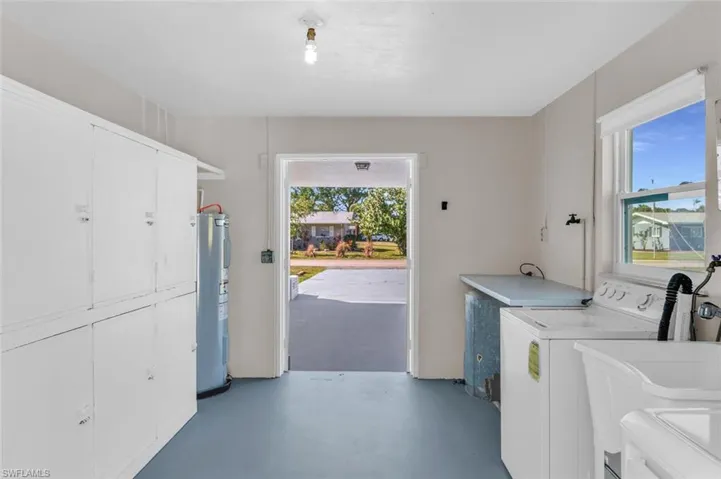 Utility room with lots of storage space, new  water heater, cabinets, sink, and washing machine and dryer. Dual Entry