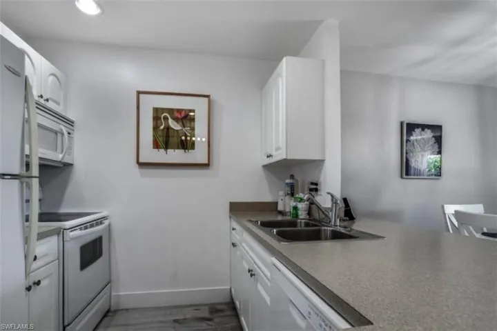 Pre Ian Kitchen with white appliances, white cabinets, and light wood-type flooring