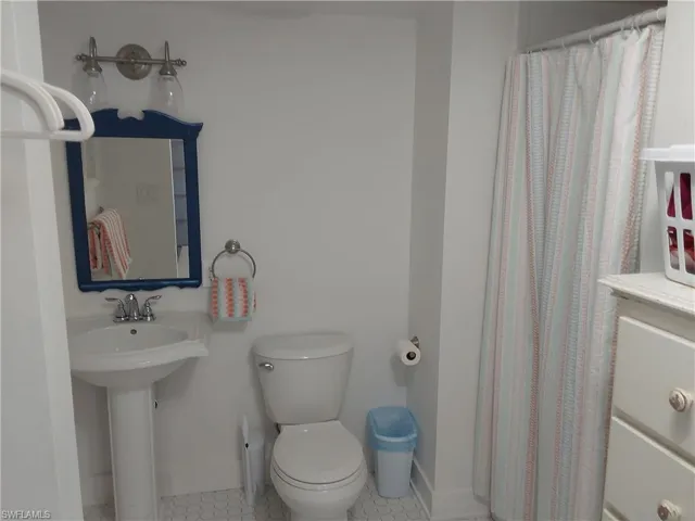 Bathroom featuring tile patterned floors, curtained shower, toilet, and sink