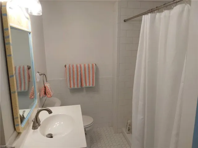 Bathroom with tile patterned flooring, toilet, sink, and walk in shower