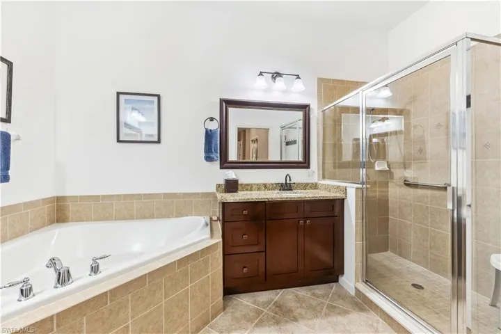 Full bath featuring vanity, a garden tub, light tile patterned flooring, and a shower stall