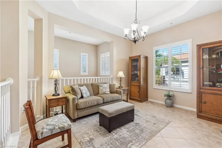 Living room featuring tile patterned flooring, a tray ceiling, and a chandelier