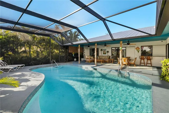 View of swimming pool featuring glass enclosure, a patio area, and an outdoor living space