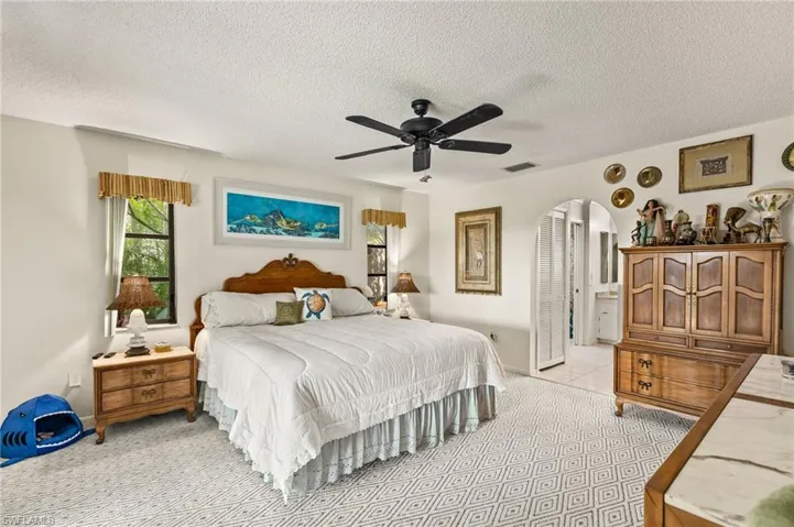 Bedroom with visible vents, ceiling fan, light tile patterned flooring, arched walkways, and a textured ceiling