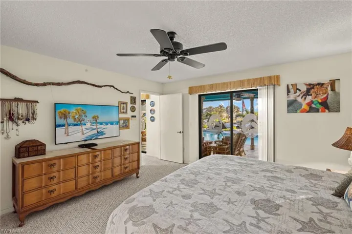 Carpeted bedroom with access to exterior, ceiling fan, and a textured ceiling