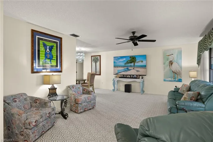 Carpeted living room featuring ceiling fan and a textured ceiling