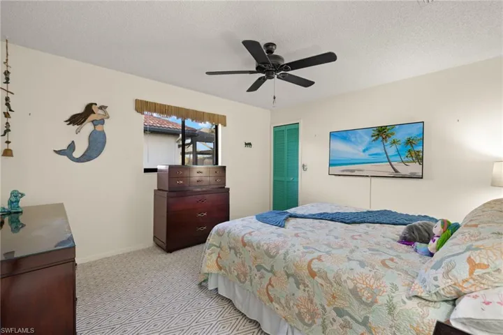 Carpeted bedroom featuring ceiling fan, a closet, and a textured ceiling