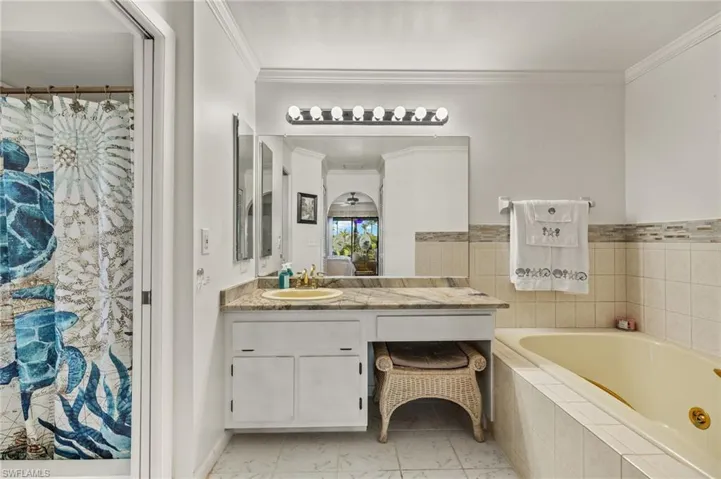 Full bath featuring vanity, crown molding, a bath, and marble finish floor
