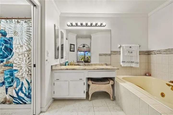 Full bathroom with vanity, crown molding, a bath, and marble finish floor