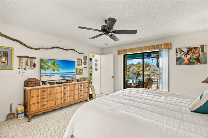 Bedroom with a textured ceiling, access to outside, a ceiling fan, and light carpet