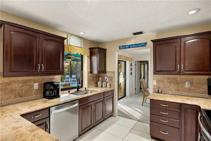 Kitchen with sink, backsplash, a textured ceiling, light carpet, and appliances with stainless steel finishes