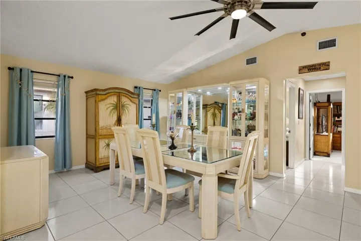 Dining space featuring ceiling fan, light tile patterned floors, and vaulted ceiling