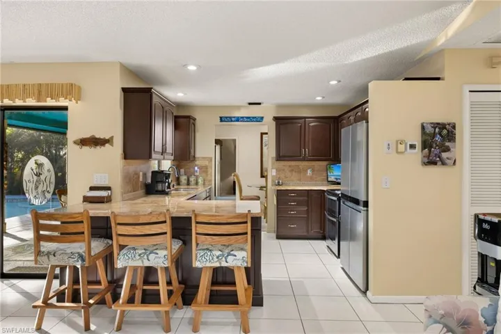 Kitchen with sink, kitchen peninsula, a breakfast bar, light tile patterned floors, and dark brown cabinets