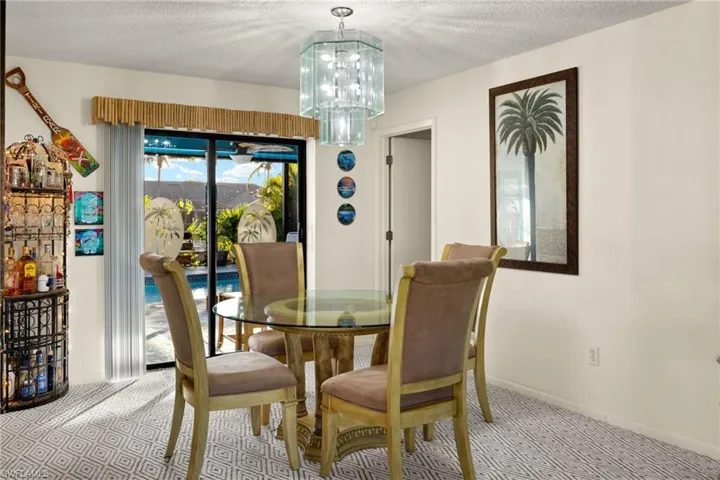 Carpeted dining room with a textured ceiling and an inviting chandelier