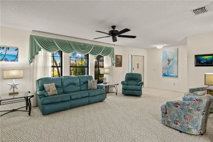 Tiled living room with ceiling fan and a textured ceiling